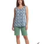 Model wearing a blue and green floral sleeveless top with green shorts against a white background, showcasing a casual summer outfit.